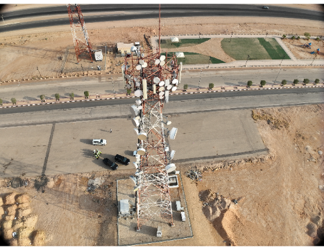 Aerial drone view of telecom tower inspection with technician on-site in Saudi Arabia