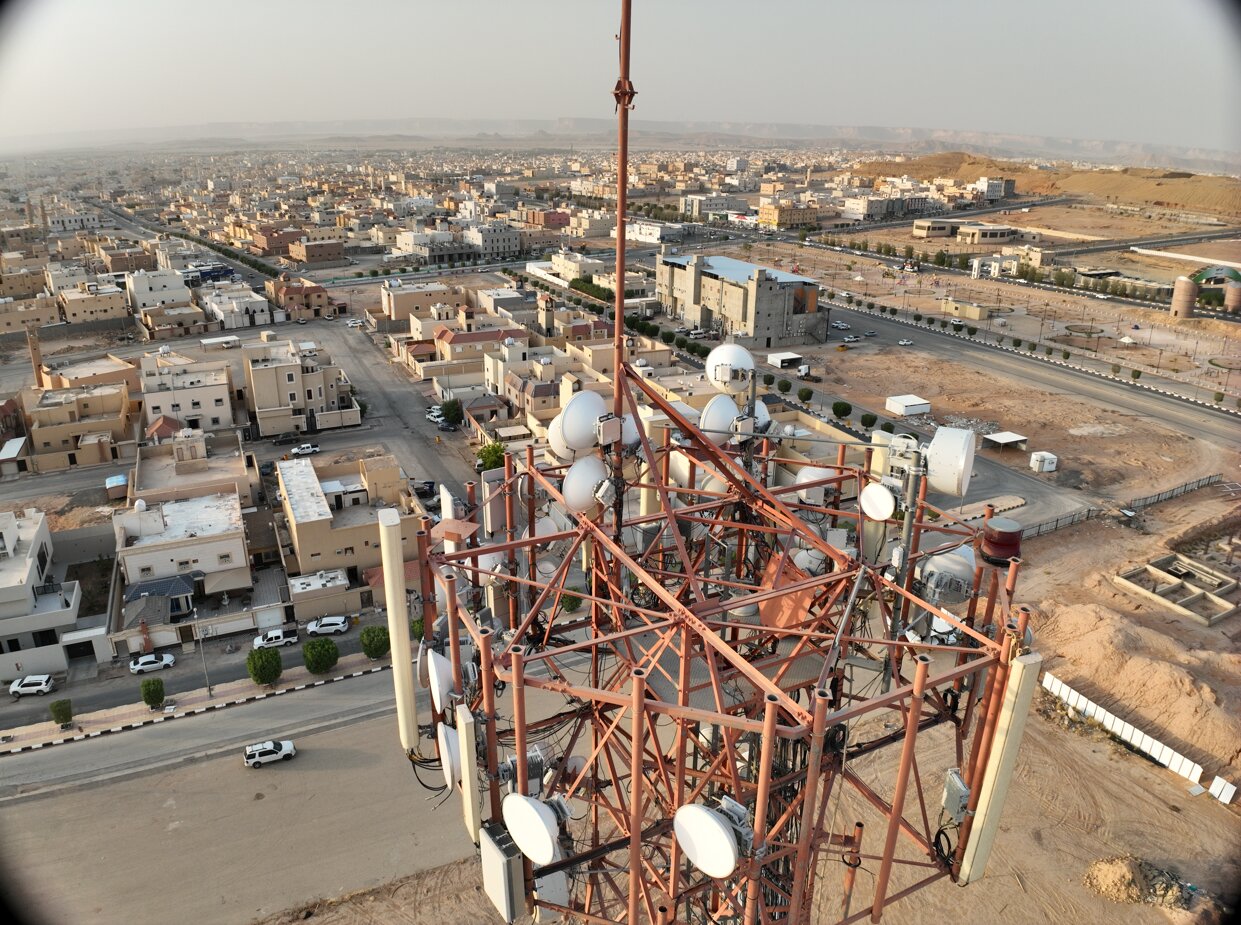 Top-down drone view of telecom tower microwave dishes and antennas during inspection in Saudi Arabia
